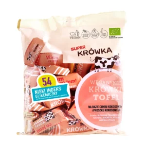 Ekologiczne wegańskie krówki bezmleczne o smaku toffi; foliowe kremowe opakowane z krówkami w papierku koloru łososiowego, przezroczyste okienko przez które widać zawartość, logo super krówka