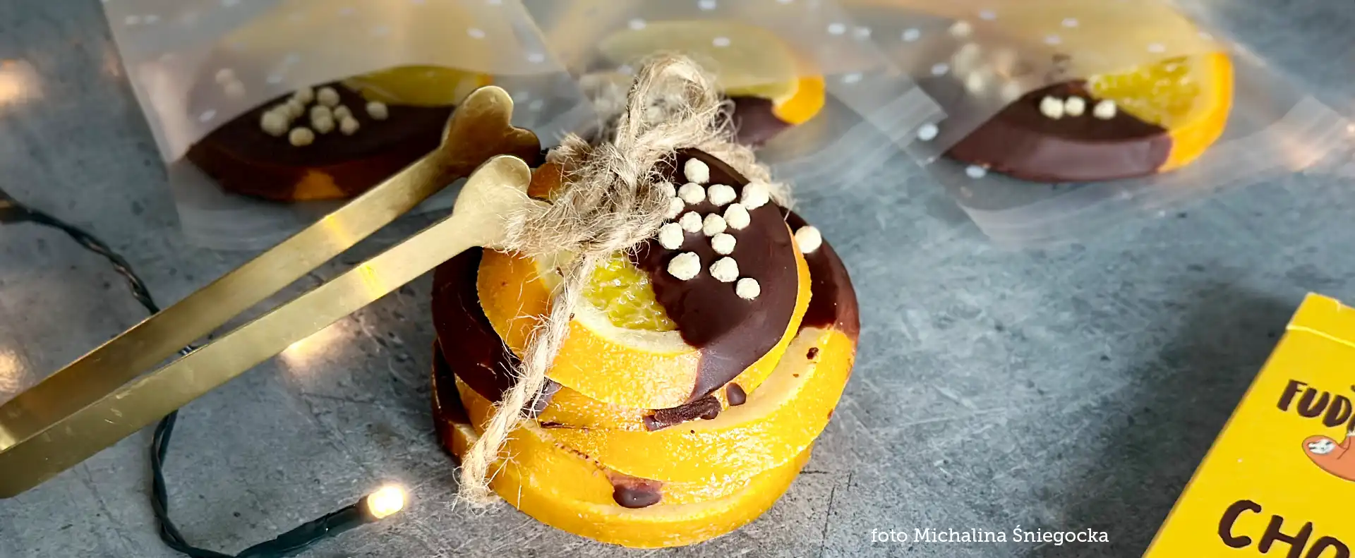 superfudgio-przepis-pomarancze-w-czekoladzie-weganskiej plastry pomarańcza w czekoladzie ułożone jeden na drugim i zwiazane, udekorowane posypką